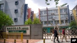 28일 베이징 주민들이 폐쇄된 초등학교 앞을 지나고 있다. 