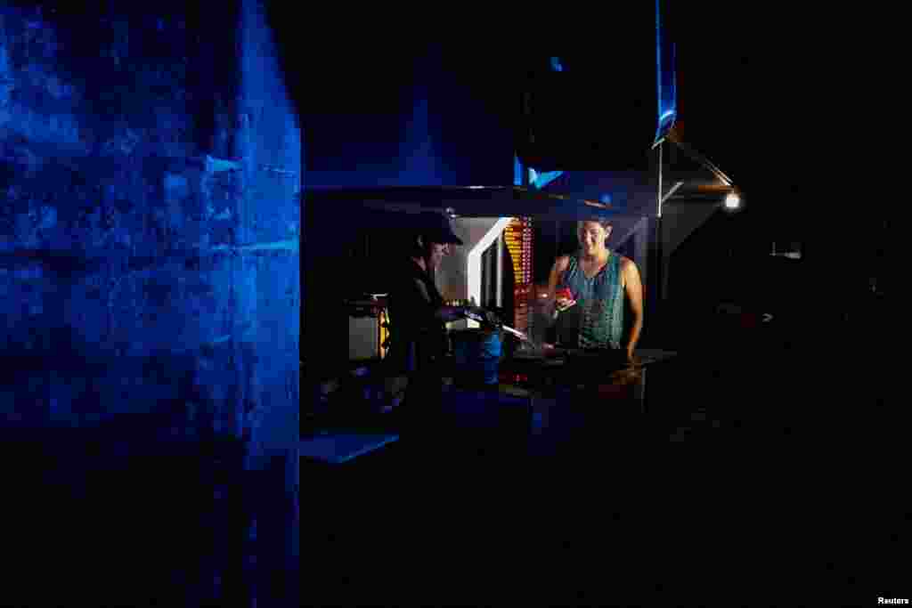 Una mujer vende comida callejera durante un apagón nacional por mantenimiento en el sistema eléctrico del país durante la noche del miércoles, en Puyo, Ecuador, el 18 de septiembre de 2024. REUTERS/Karen Toro 