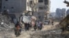 Palestinos caminan entre la destrucción dejada por la campaña aérea y terrestre israelí en Jan Yunis, en el sur de la Franja de Gaza, el domingo 7 de abril de 2024.