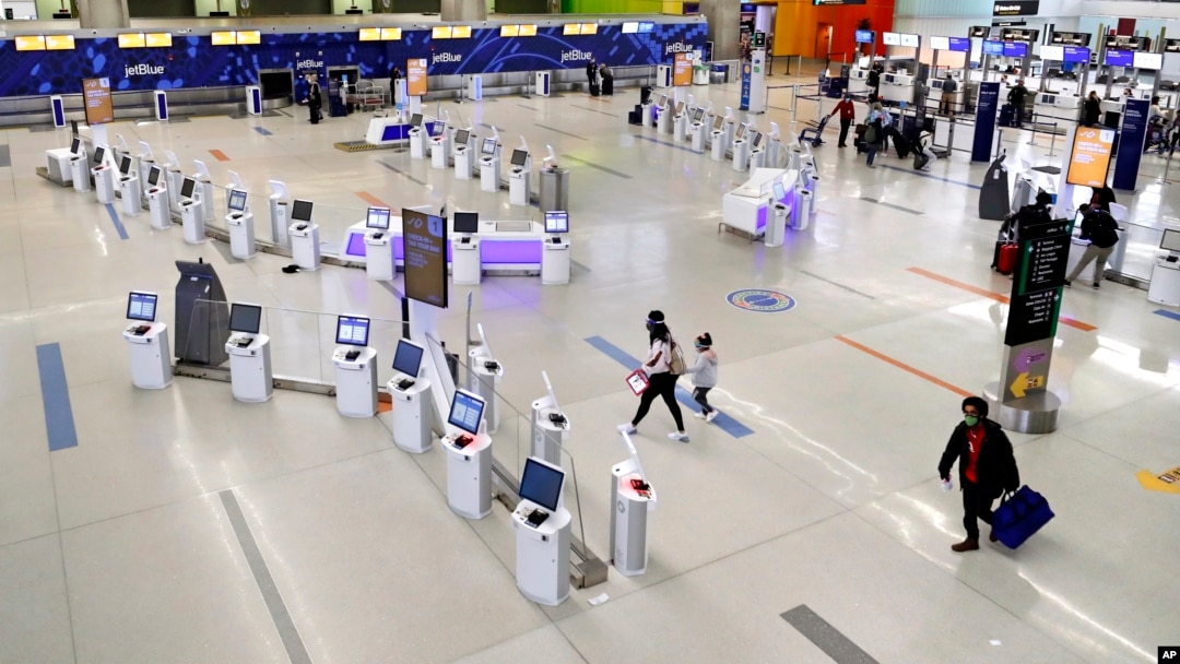 FILE - Travelers walk through the nearly empty JetBlue terminal at Logan Airport on Nov. 20, 2020, in Boston, Massachusetts. (AP Photo/Michael Dwyer)