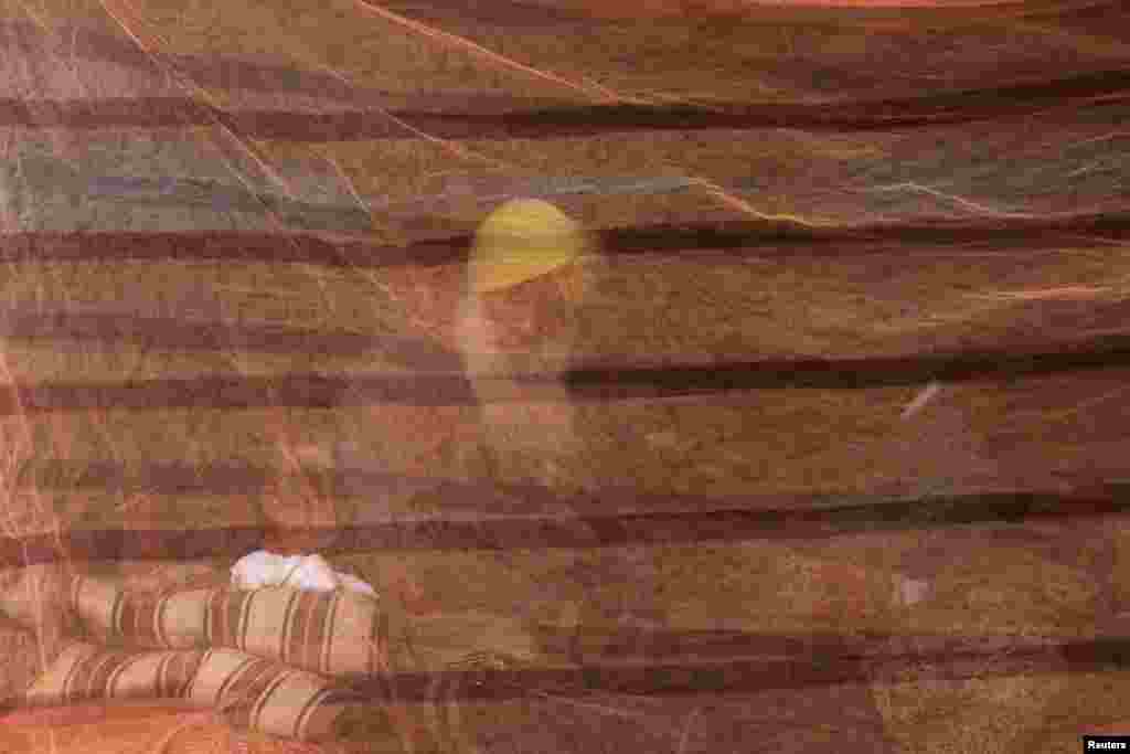 A farmer is seen through a mosquito net at a site of a protest against the newly passed farm bills at Singhu border near New Delhi, India.