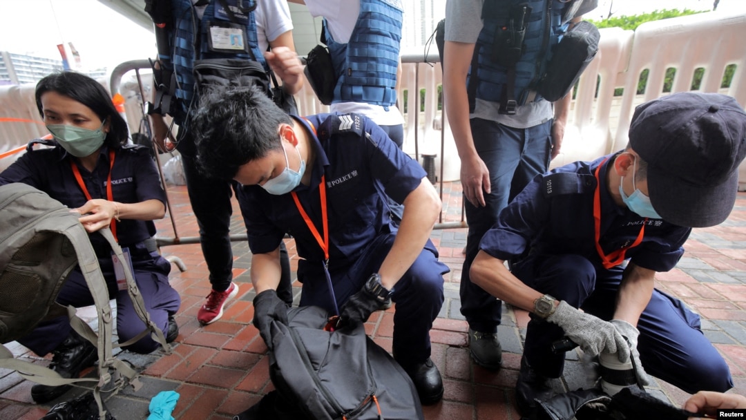 FILE - Police inspect journalists' bags at a media position outside the Hong Kong West Kowloon railway station, in Hong Kong, China, June 30, 2022.