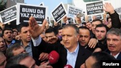 Zaman editor-in-chief Ekrem Dumanli, surrounded by his colleagues and plainclothes police officers (C), reacts as he leaves the headquarters of Zaman daily newspaper in Istanbul December 14, 2014. (REUTERS/Yagiz Karahan )