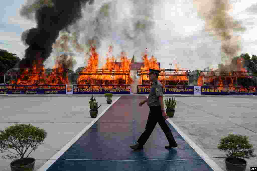 A police officer walks in front of a burning pile of seized illegal drugs during a destruction ceremony to mark the United Nations' International Day Against Drug Abuse and Illicit Trafficking in Yangon, Myanmar.