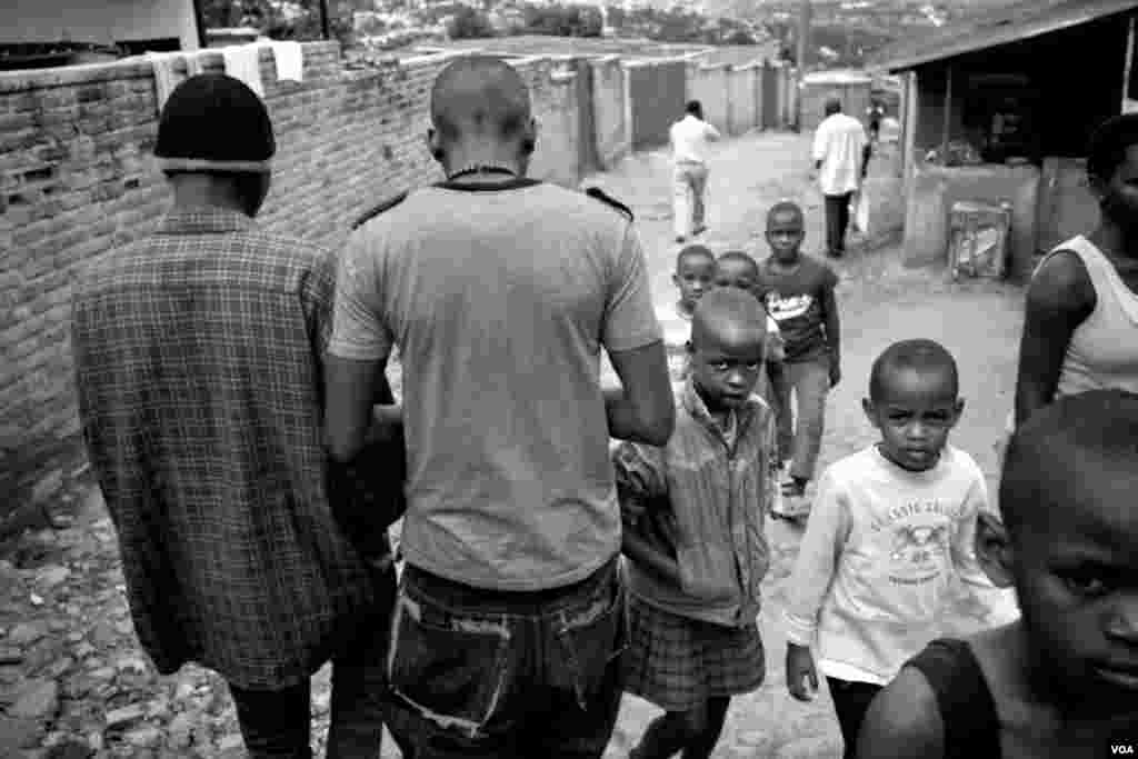 Nshizirungu Amos (kiri) dan Vansing berjalan di antara anak-anak kecil di jalanan Giporoso, Kigali. (VOA/Hamada Elrasam)