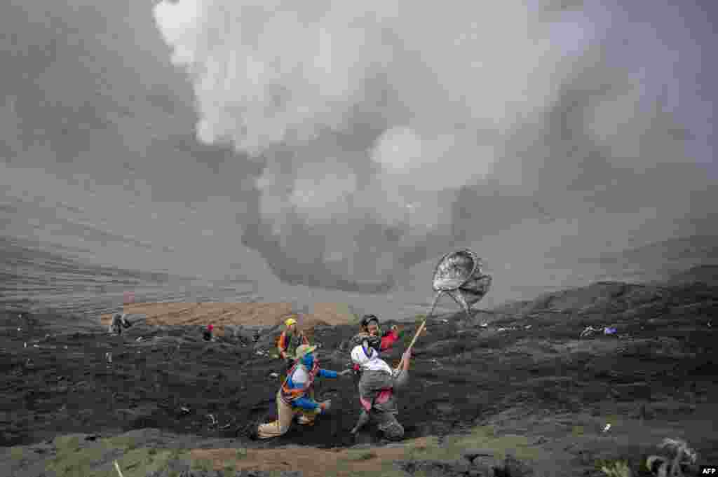 Villagers catch coin offerings released by Hindu devotees of the Tengger tribe during the Yadnya Kasada festival, on the crater of Mount Bromo in Probolinggo, Indonesia. During the annual festival the Tenggerese climb Mount Bromo, an active volcano, and seek the blessing from the main deity Hyang Widi Wasa by presenting offerings of rice, fruit, livestock and other local produce.