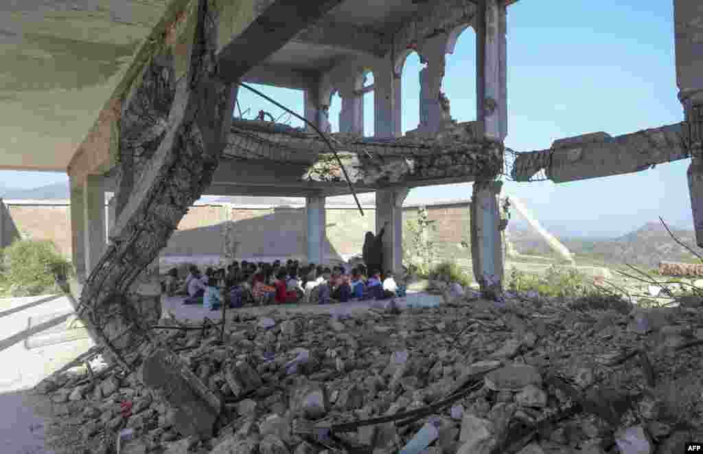 Yemeni pupils attend class on the first day of the new academic year, in a makeshift classroom in their school compound which was heavily damaged two years ago in an airstrike, in the country's third-city of Taez.