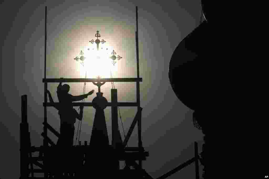 Workers prepare for the restoration of a cross on the Church of the Life-Giving Trinity in Ostankino, a monument of old Russian cult architecture, during sunset in Moscow, Russia, Aug. 5, 2020.