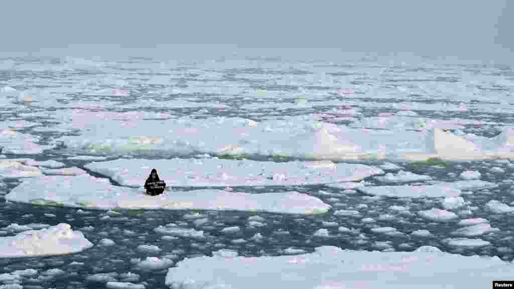 Environmental activist and campaigner Mya-Rose Craig, 18, holds a cardboard sign reading "youth strike for climate" as she sits on the ice floe in the middle of the Arctic Ocean, hundreds of miles above the Arctic Circle.