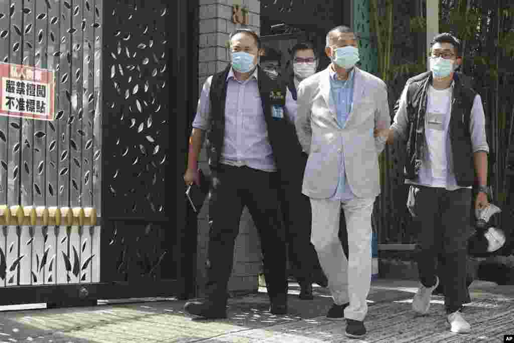 Hong Kong media tycoon Jimmy Lai, center, who founded local newspaper Apple Daily, is arrested under the new national security law by police officers at his home. Lai was arrested on suspicion of collusion with foreign powers, his aide said.