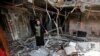 FILE - Raghad Hammoudi, a member of a group of students campaigning to help rebuild the Central Library of Mosul University, stands amid rubble in Mosul, Iraq, May 14, 2018. 