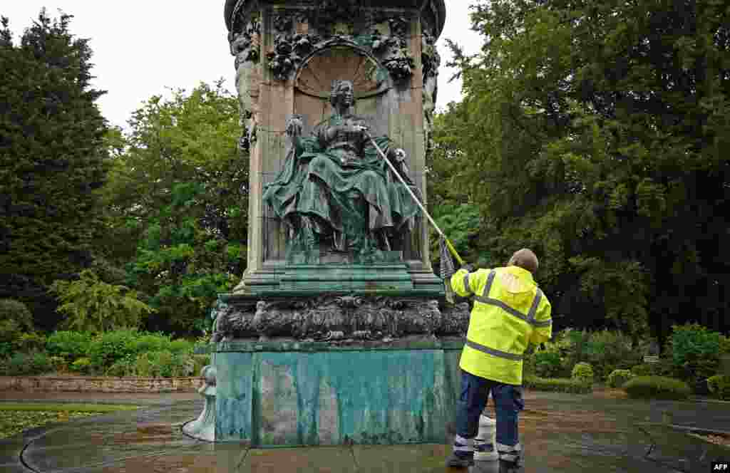 Council workers clean a statue of Britain's Queen Victoria that was defaced in Woodhouse Moor Park in Leeds, northern England.