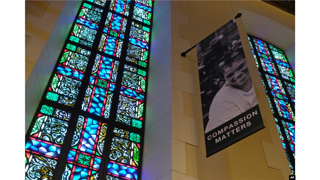 In this Feb. 12, 2019 photo, a banner hangs by a stained glass window in the sanctuary at Glide Memorial United Methodist Church in San Francisco.