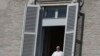 Pope Francis leans out of his studio window overlooking St. Peter's Square at the Vatican, March 15, 2020. 