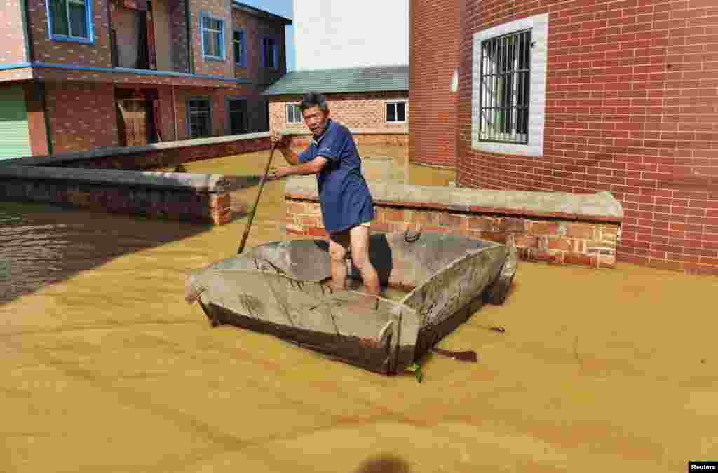 Seorang pria mendayung di sepanjang daerah pejalan kaki yang terendam banjir di Kabupaten Poyang, Provinsi Jiangxi, China, 21 Juni 2016.
