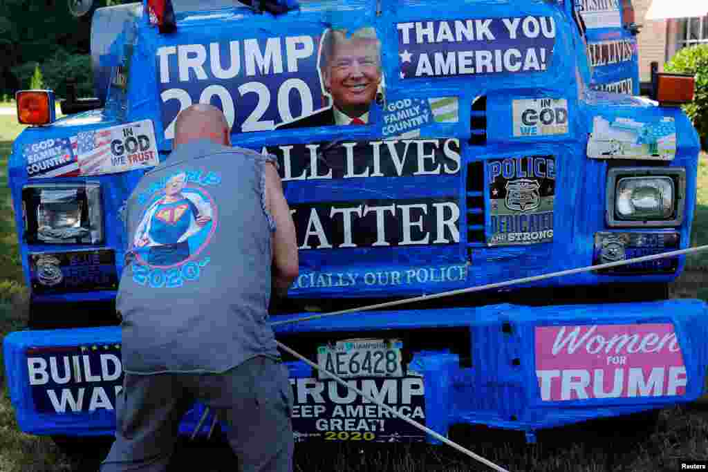 A supporter of U.S. President Donald Trump ties off a banner hanging from a boom during Super Happy Fun America's "Back the Blue/President Trump Standout" in Stoneham, Massachusetts, July 27, 2020.