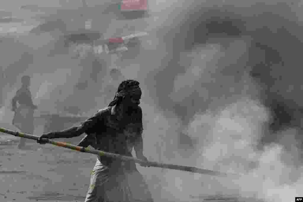 A worker prepares bitumen and rock mixtures to be used to repair a road in Dhaka, Bangladesh.