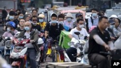 在這張日期為 2021 年 7 月 2 日星期五的文件照片中，北京高峰時段騎自行車和踏板車的人們等待穿過十字路口。聯合國氣候變化官員於 2021 年 7 月 31 日星期六表示，中國未能提交減少溫室氣體排放的新目標，其中數十個未能在 7 月 31 日截止日期前提供其計劃的最新信息。 （美聯社照片）