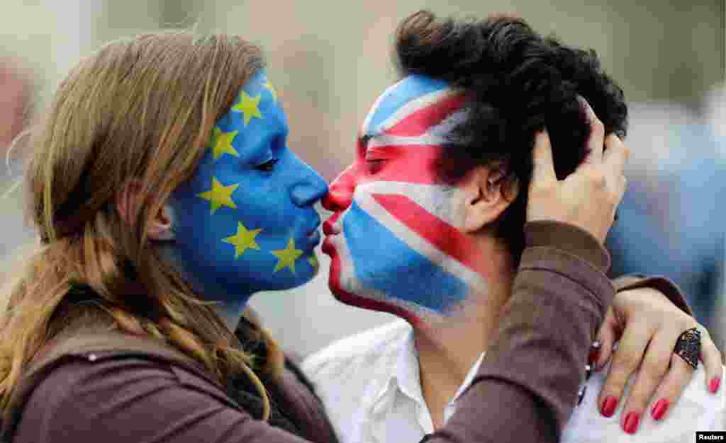 Dua muda-mudi dengan cat wajah bendera Uni Eropa (kiri) dan bendera Inggris 'Union Jack' (kanan) berciuman di depan gerbang Brandenburg di Berlin, Jerman untuk menentang "Brexit".