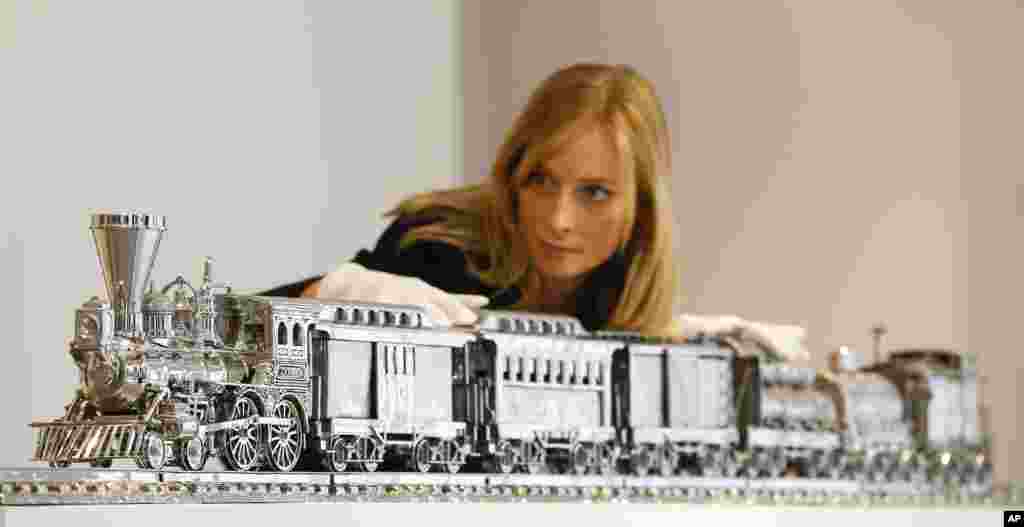 Seorang karyawati dari rumah lelang Christie berpose dengan "Kereta Stainless steel dan Bourbon Jim Beam-J.B.Turner" karya Jeff Koons yang dipamerkan di rumah lelang di London. 