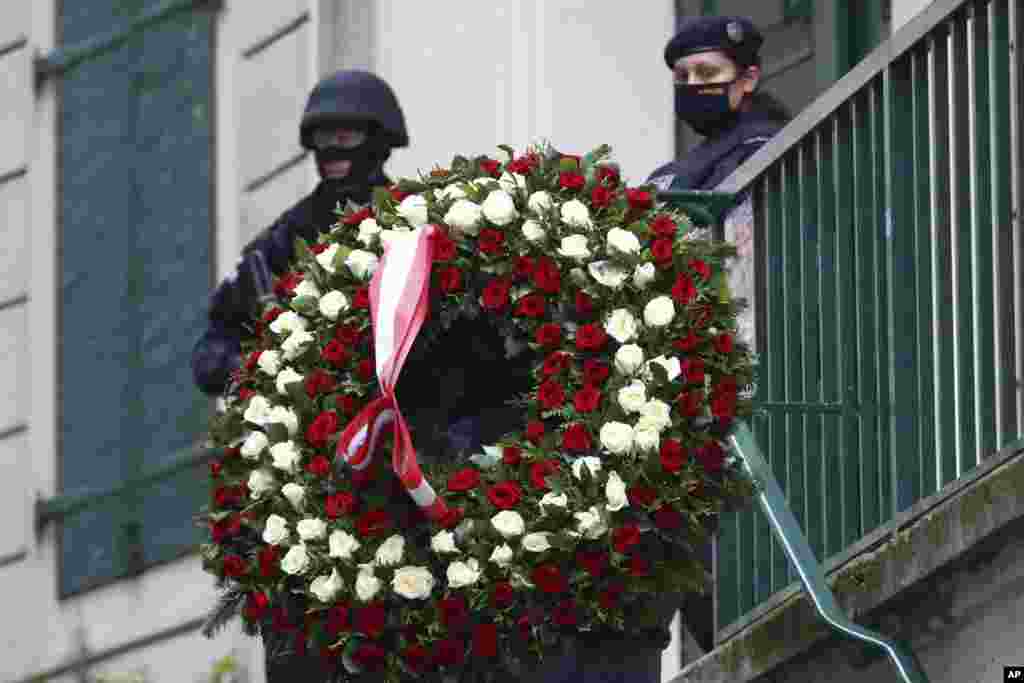 A man carries a wreath as he walks past police officers in Vienna, Austria. A deadly rampage left four dead and at least 15 wounded in multiple locations in the city in what Austrian Chancellor Sebastian Kurz labeled a “repulsive terror attack.” 