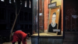 A person places flowers in front of a painting in a storefront on Broadway of Associate Justice of the Supreme Court of the United States Ruth Bader Ginsburg who passed away in Manhattan, New York City, U.S., September 18, 2020.