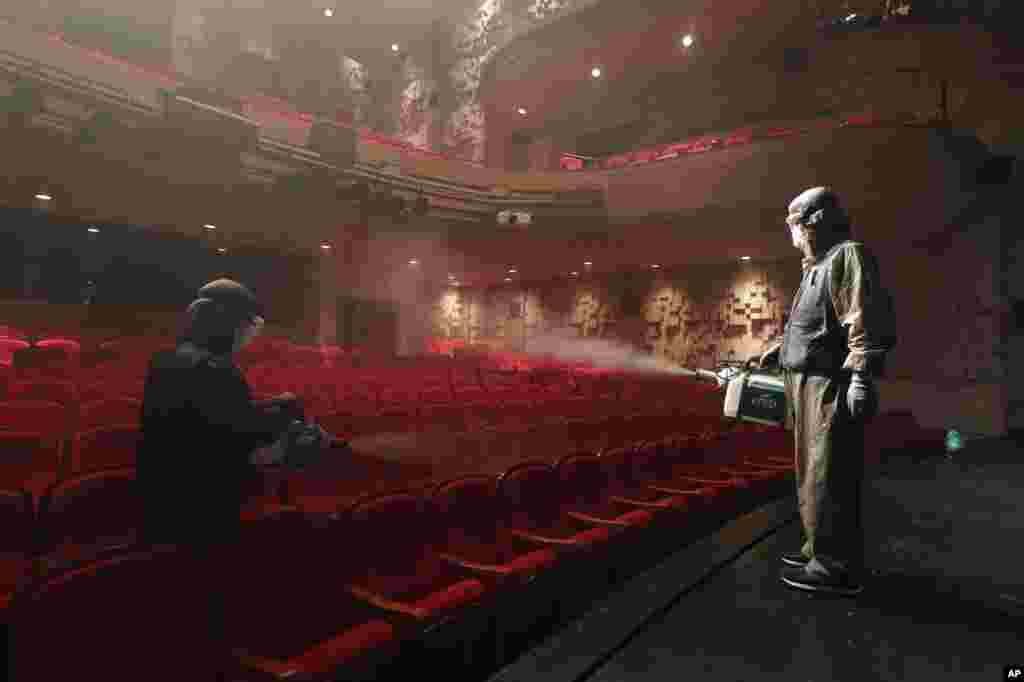 Workers wearing protective gears spray disinfectant as a precaution against a new coronavirus at a theater in Sejong Center in Seoul, South Korea.