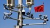 Una bandera china ondea cerca de cámaras de vigilancia montadas sobre un poste de luz en la plaza de Tiananmen, en Beijing.