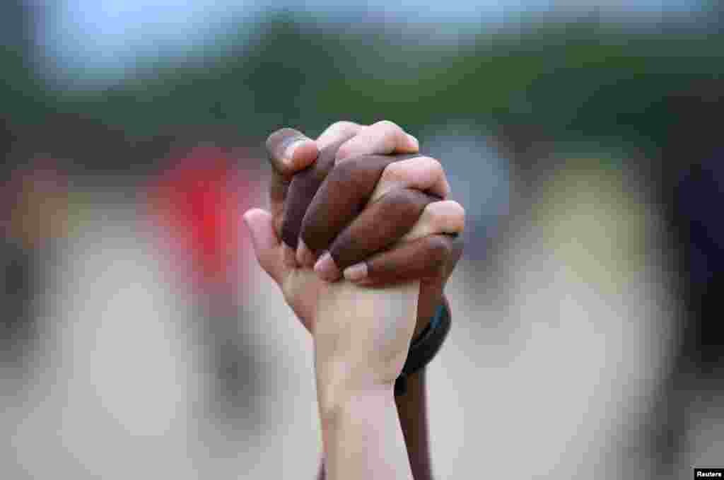 A man and a woman hold hands aloft in Hyde Park during a "Black Lives Matter" protest in London, following the death of George Floyd who died in police custody in Minneapolis, USA.