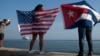 FILE - Yaney Cajigal, left, and Dalwin Valdes display flags for the U.S. and Cuba while awaiting the arrival of a Carnival cruise ship from Miami to Havana, Cuba, May 2, 2016. The Florida Straits had been closed to most U.S.-Cuba traffic for decades.