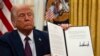 President Donald Trump holds up a signed executive order relating to the Lumbee Tribe of North Carolina in the Oval Office of the White House, Thursday, Jan. 23, 2025, in Washington. (AP Photo/Ben Curtis)