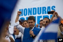 Honduran President Juan Orlando Hernandez raises his right fist as he mets with his party base, in Tegucigalpa, Honduras, Thursday, Dec. 7, 2017.
