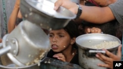 Un niño palestino observa mientras le sirven una ración de comida antes de la fiesta del Eid al-Adha, en Jan Yunis, Gaza, el 15 de junio de 2024. 