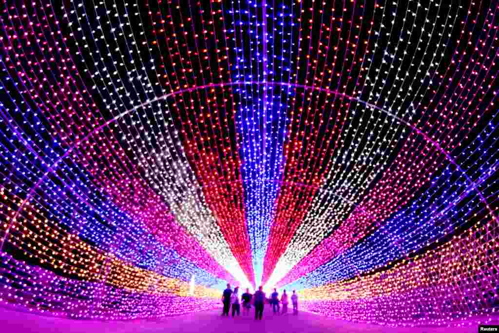 Para turis melewati karya seni 'instalasi lentera' di Zhangjiakou, Hebei, China.