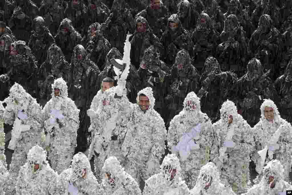 Mengenakan pakaian ghilli, pasukan tentara Iran berbaris dalam parade di mana salah seorang dari mereka mengacungkan senjatanya, menandai hari angkatan bersenjata nasional di depan makam pendiri revolusioner mendiang Ayatollah Khomeini di Teheran. 