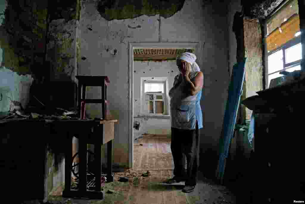 Local resident Katerina Izvekova, 77, shows her house damaged during a military conflict between militants of the self-proclaimed Donetsk People's Republic and the Ukrainian armed forces in the rebel-controlled village of Vesele (Veseloye) in Donetsk region.