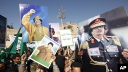 File - Supporters of Libyan leader Moammar Gadhafi hold his pictures as they take part in a pro-government rally in Tripoli, February 17, 2011