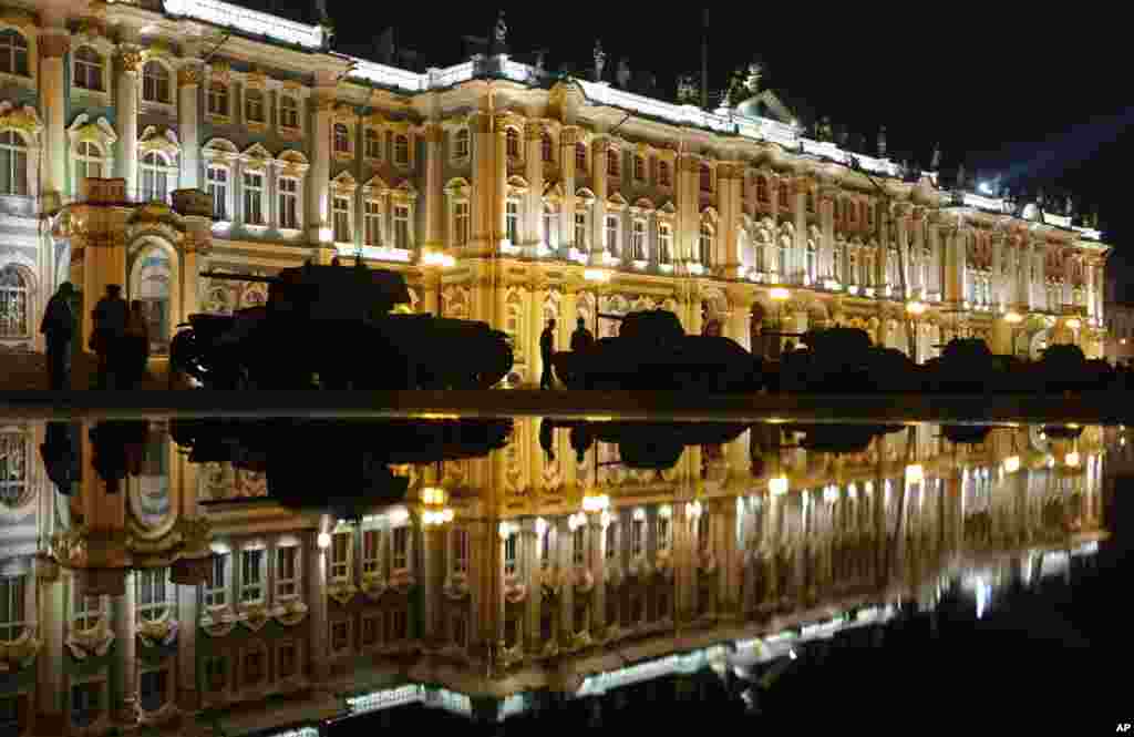 Orang-orang melintasi tank-tank dari masa Perang Dunia II di pagi hari, saat yang sama ketika Nazi Jerman menyerang Uni Sovyet 75 tahun yang lalu di Lapangan Dvortsovaya (Istana) di St. Petersburg, Rusia, dengan istana Zimny (Musim Dingin) di latar belakang.