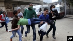 Egyptians carry a protester wounded in clashes with security forces near Tahrir square, where an opposition rally has been called for to voice rejection of President Morsi's seizure of near absolute powers in Cairo, Egypt, November 27, 2012.