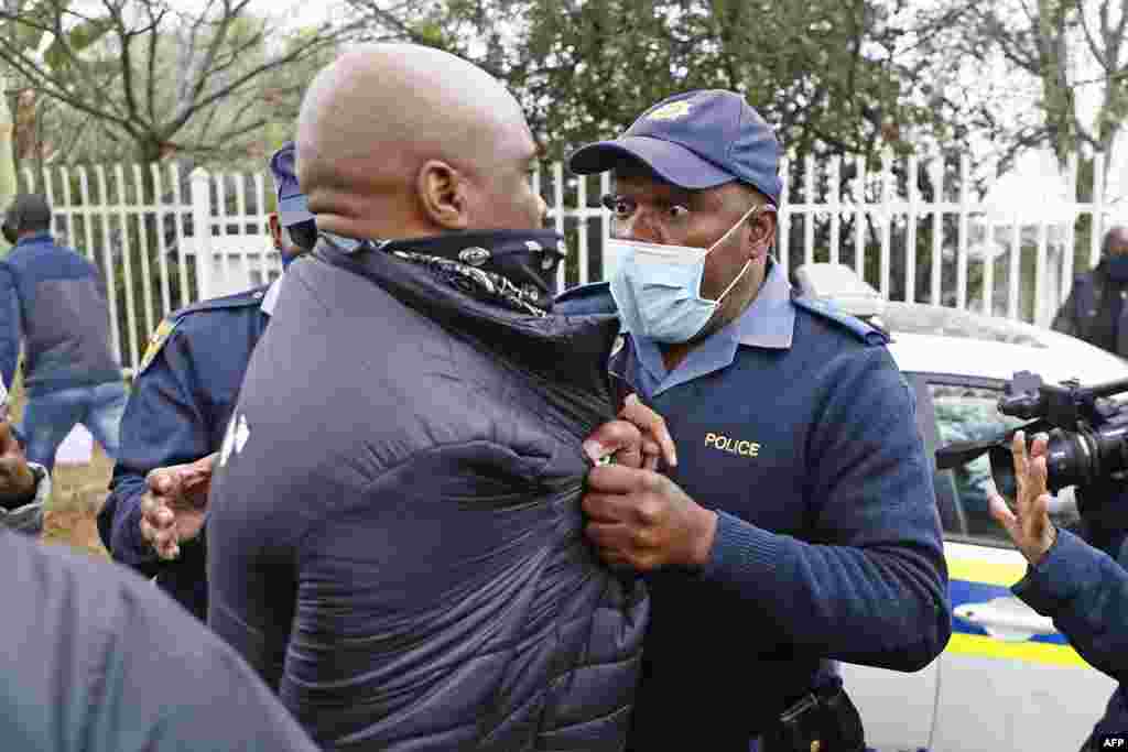 A South African police member grabs a protester during their picket against the government of Zimbabwe's alleged state corruption, media freedom and deteriorating economy outside the Zimbabwean Embassy in Pretoria.