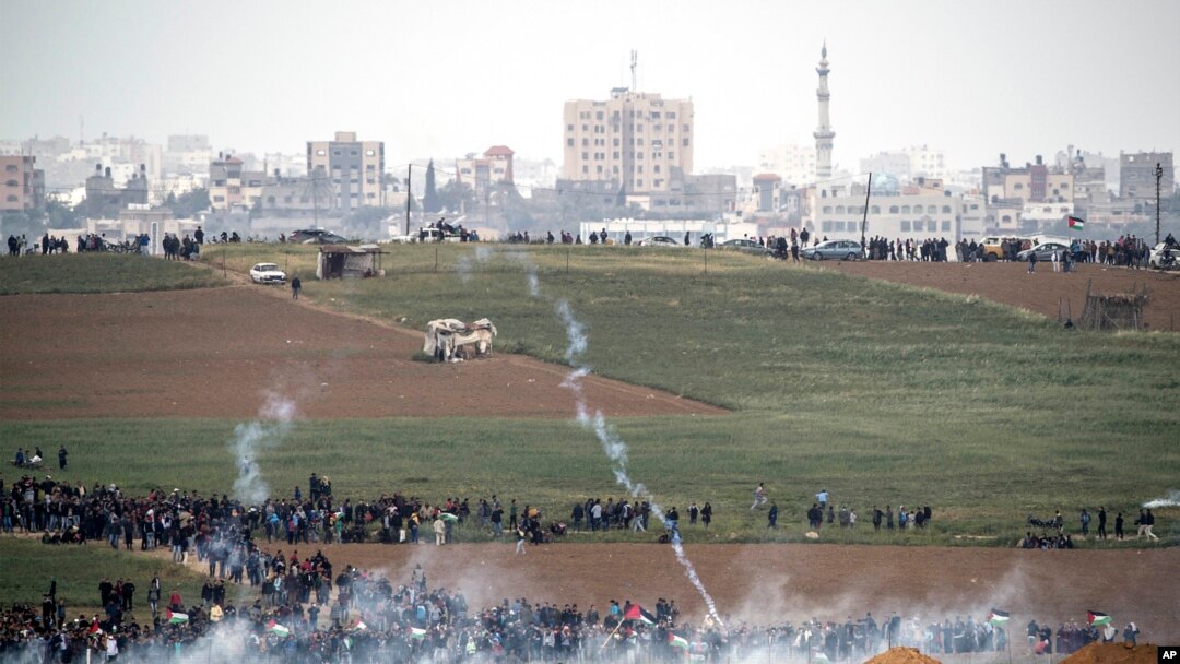 Askari wa Israeli wakirusha mabomu ya machozi kuwasambaza waandamanaji wa Palestina katika mpaka wa Gaza, Machi 30, 2018. 