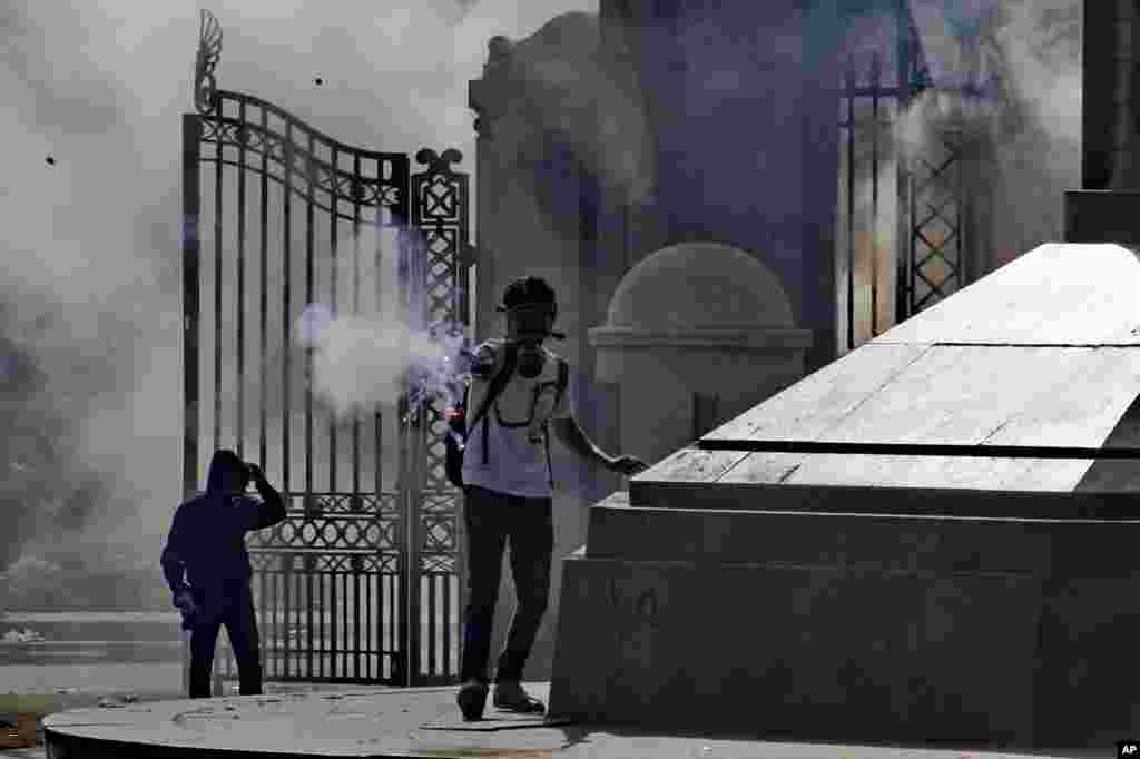 Seorang demonstran menembakkan pijar dalam bentrokan dengan pasukan keamanan di luar Cairo University di Giza (26/3). (AP/Ahmed Abdel Fattah, El Shorouk) 