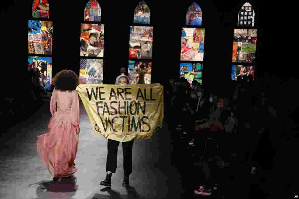 An activist displays a banner during Dior's Spring-Summer 2021 fashion collection presented during the Paris fashion week in Paris, France.