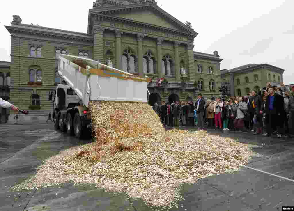 A truck dumps five-Rappen coins in the center of the Federal Square during a an event organized by the Committee for the initiative "CHF 2,500 monthly for everyone" (Grundeinkommen) in Bern, Switzerland. The Committee delivered 126,000 signatures to the Chancellery to propose a change in the constitution to implement their initiative which aims to have a minimum monthly disposal household income of CHF 2,500 (US$ 2,700) given by the government to every citizen living in Switzerland.