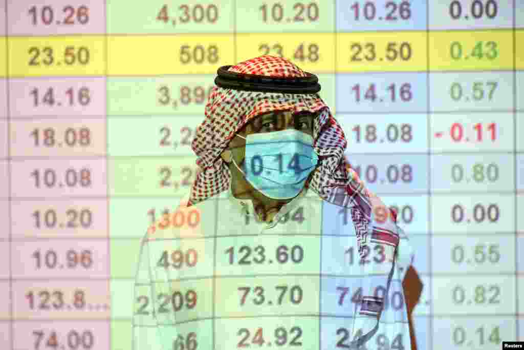 A Saudi trader wears a mask as he monitors stock information at the Saudi stock market in Riyadh, Saudi Arabia.
