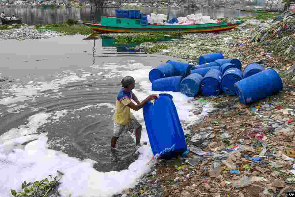 A worker cleans barrels used to contain chemicals in Buriganga river in Dhaka, Bangladesh.