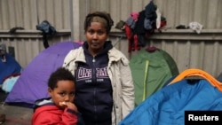 FILE - Tsega, 38, a migrant who fled Eritrea six years ago, poses with her son Naher, 5, in front of their tent at a migrant shelter in Calais, northern France, October 2014.