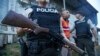 ARCHIVO - Un agente de policía hace guardia mientras una persona es detenida durante un registro en busca de armas o drogas, dentro de una operación para luchar contra las bandas criminales, en el vecindario de Nueva Guayaquil, en Guayaquil, Ecuador, el 4 de abril de 2024. 