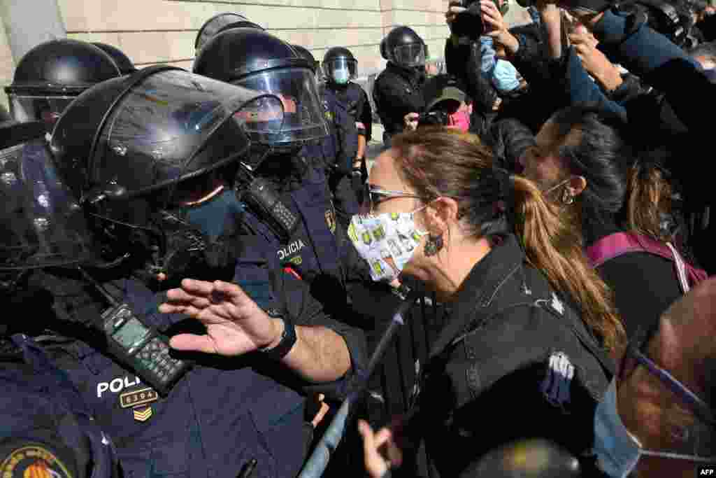 Demonstrators protest in front of Catalan regional police during a protest against the new restrictions imposed by the regional government on bars and restaurants to fight the spread of COVID-19 disease, in Barcelona.