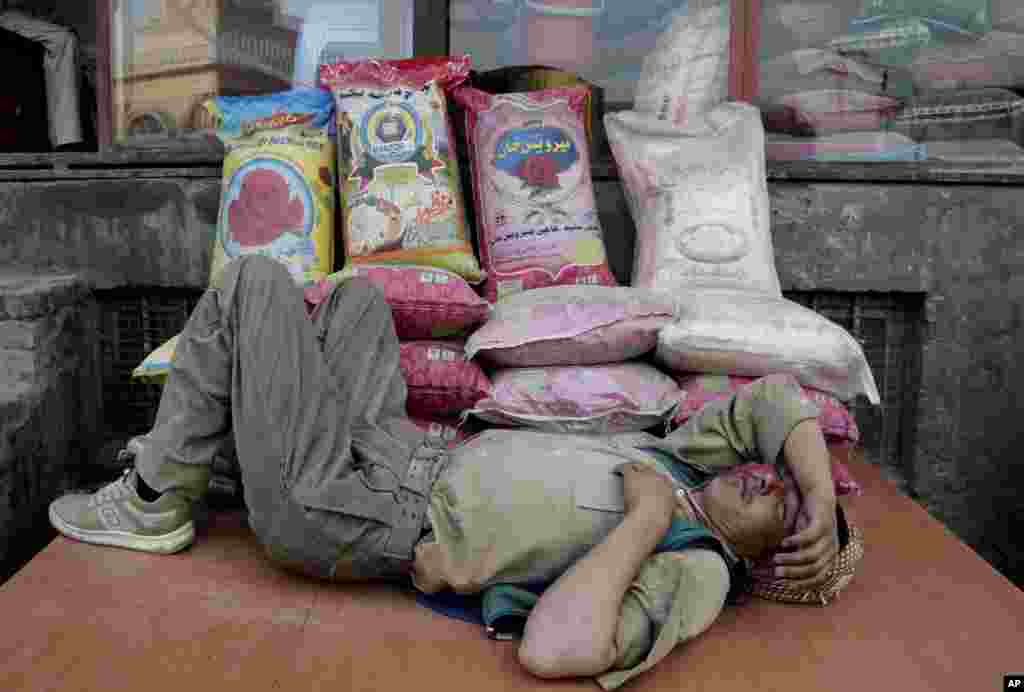 Seorang pria Afghanistan tidur siang saat istirahat dari pekerjaannya di sebuah toko beras di pasar di ibukota Kabul, Afghanistan.